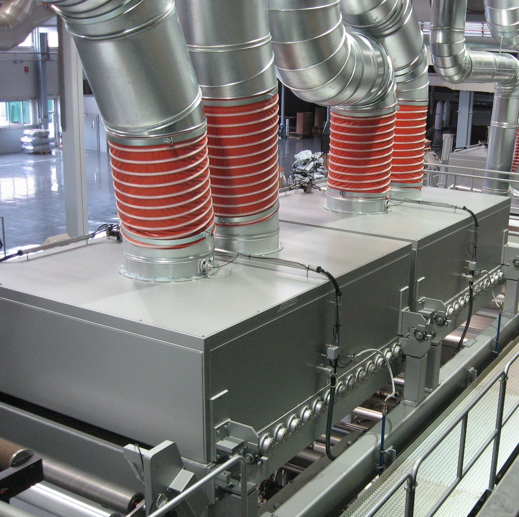 Una fila de tubos de metal con una manguera roja unida a ellos.