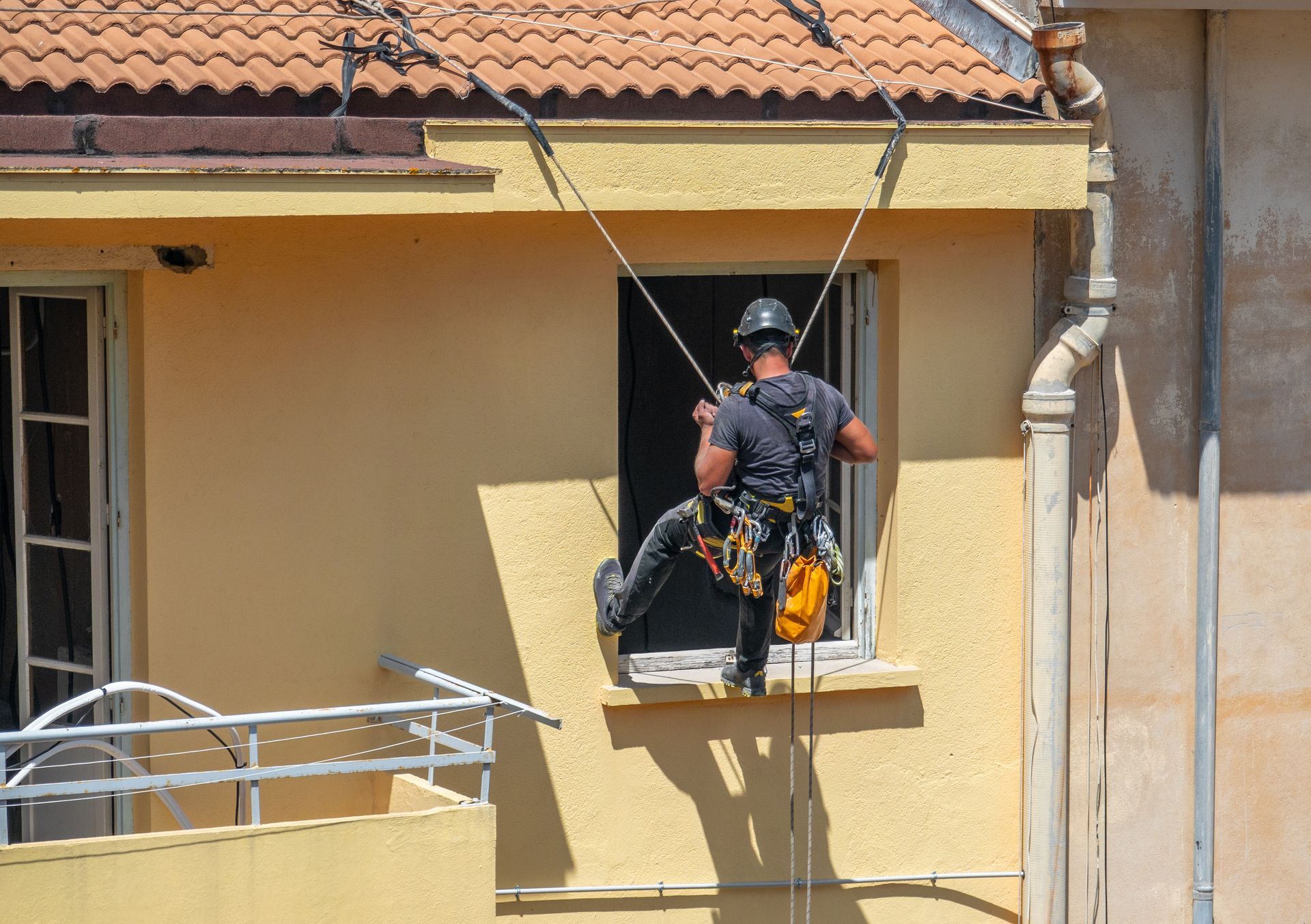Un technicien travaillant sur des cordes descend en rappel la façade d'un bâtiment.