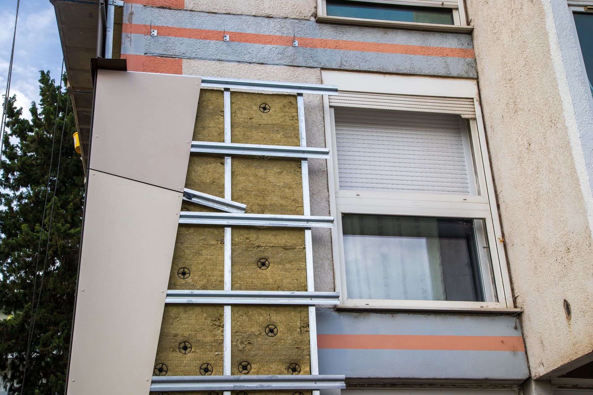 Installation de l'isolation des murs extérieurs ; cadre métallique maintenant les panneaux d'isolation sur la façade du bâtiment.