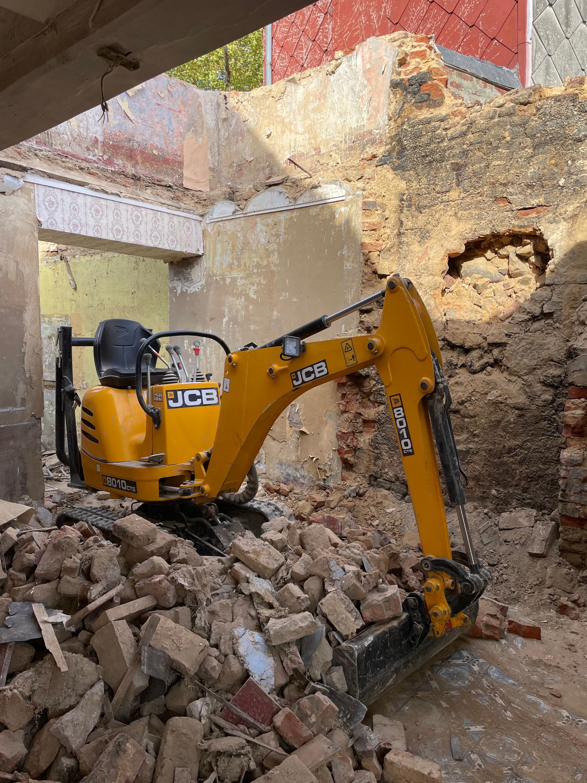 Une petite pelleteuse JCB jaune se trouve au milieu d'un tas de gravats