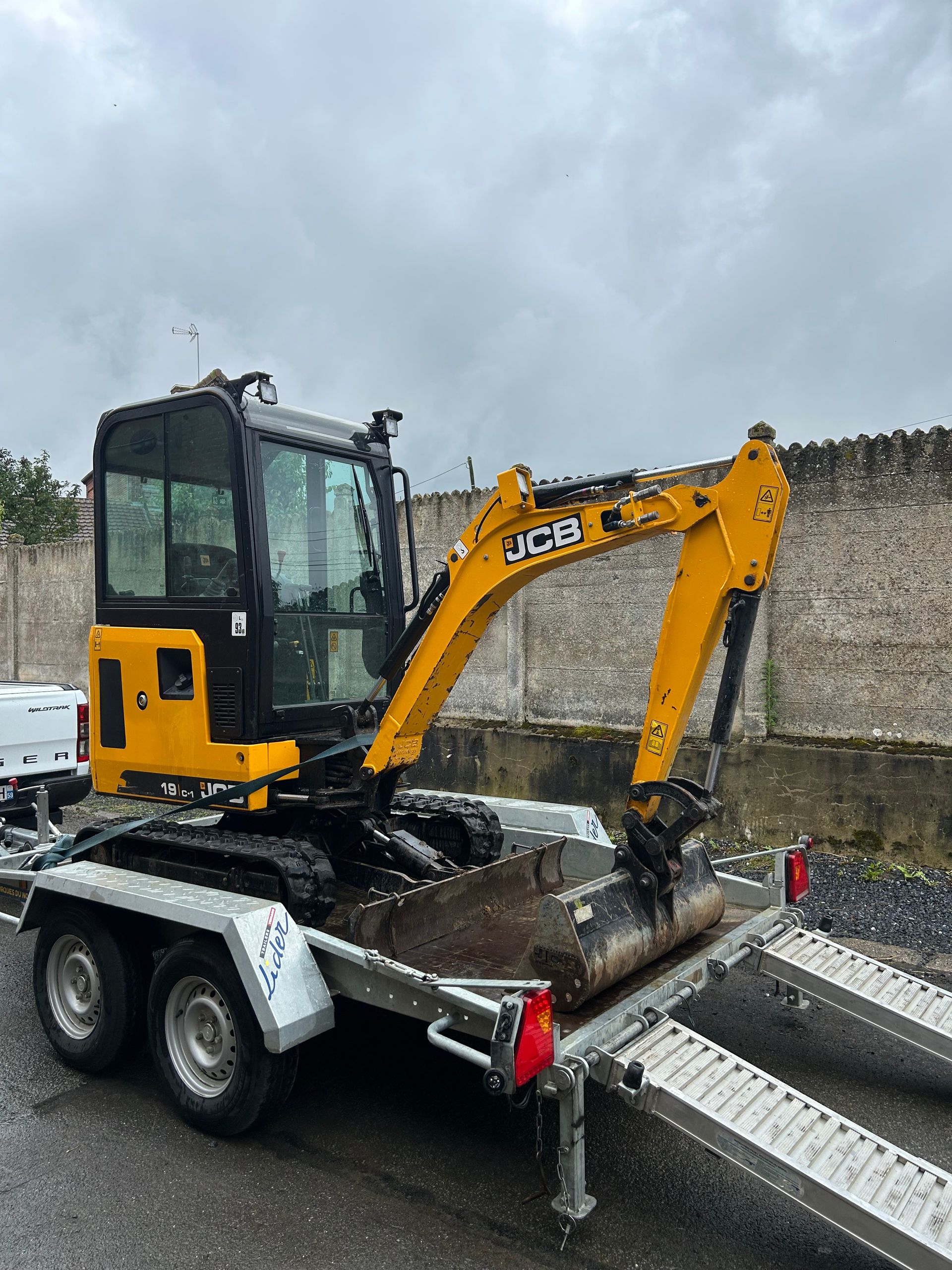Une minipelle JCB jaune est chargée sur une remorque-plateau