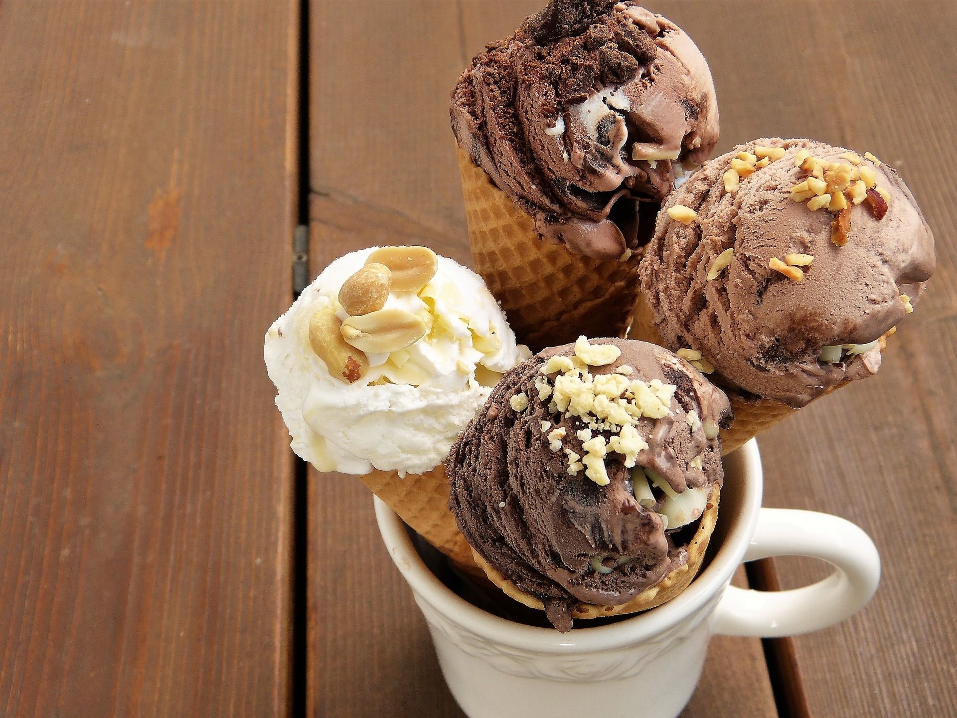 Cuatro conos de helado en una taza sobre una mesa de madera