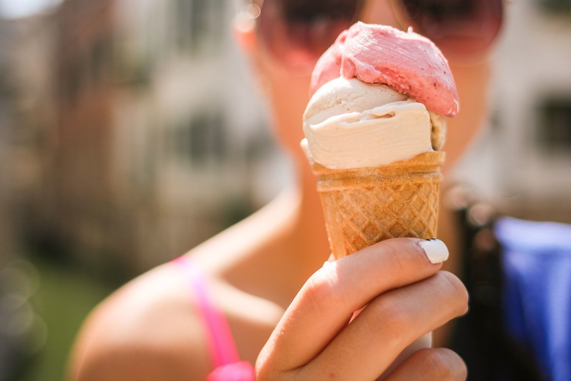 Una mujer sostiene dos conos de helado en su mano.