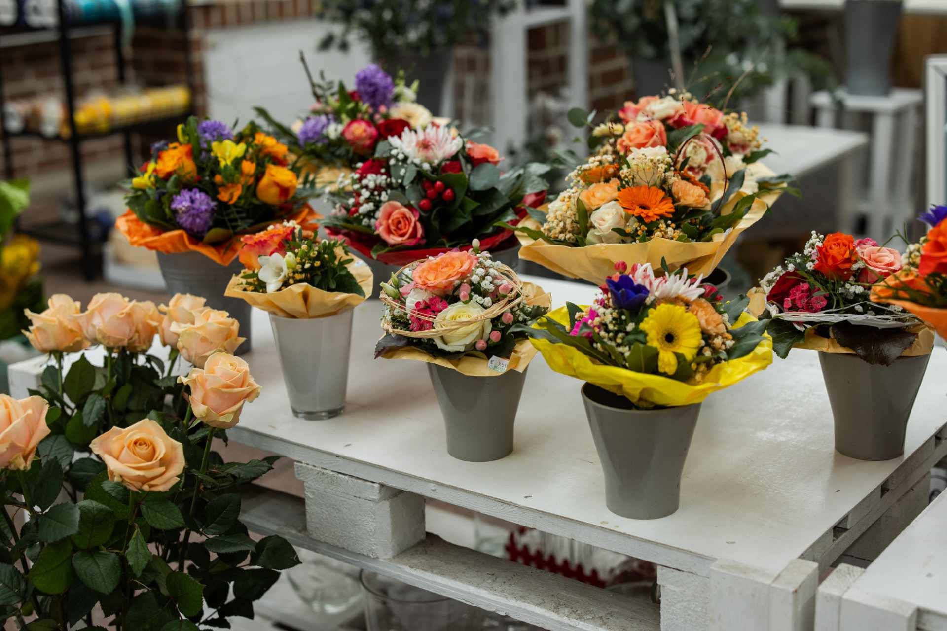 Auf einem Tisch stehen viele Blumen in Töpfen .