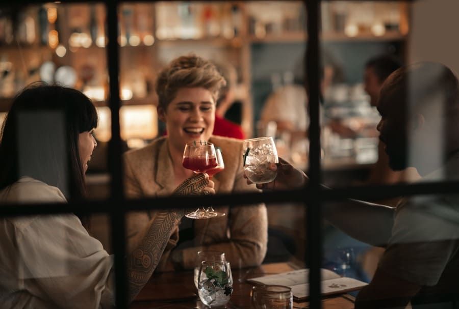 Un grupo de personas está sentada en una mesa en un restaurante bebiendo vino.