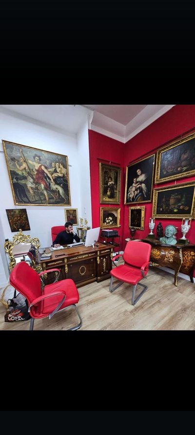 Un hombre está sentado en un escritorio en una habitación con pinturas en la pared.