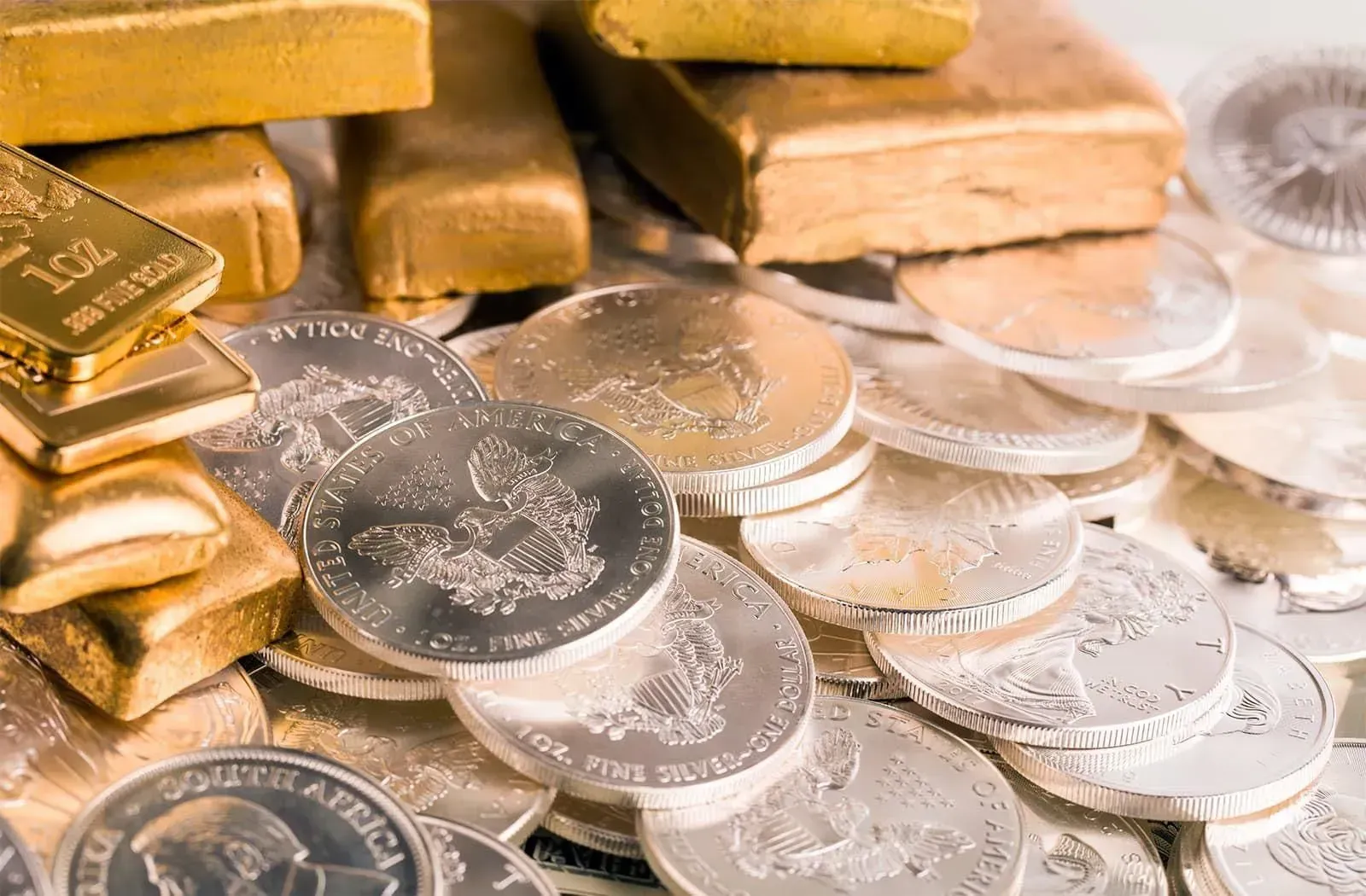 Una pila de lingotes de oro y monedas de plata sobre una mesa.