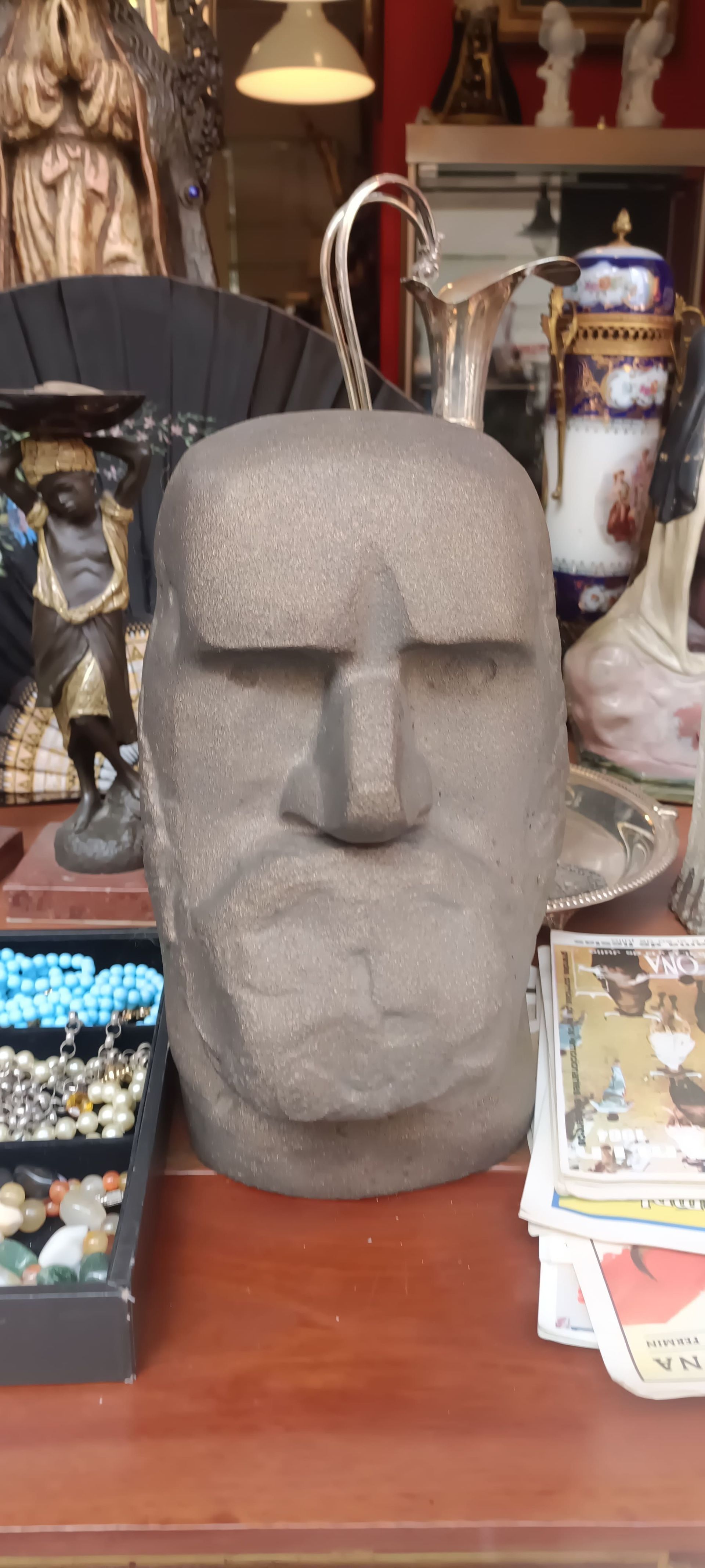 Una estatua de la cabeza de un hombre está sentada sobre una mesa de madera.