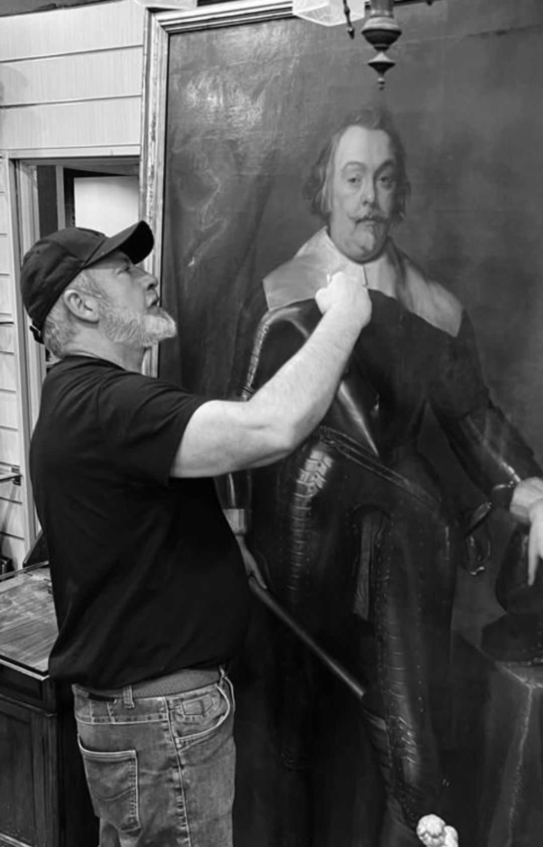 Un hombre está de pie junto a una pintura grande de un hombre.