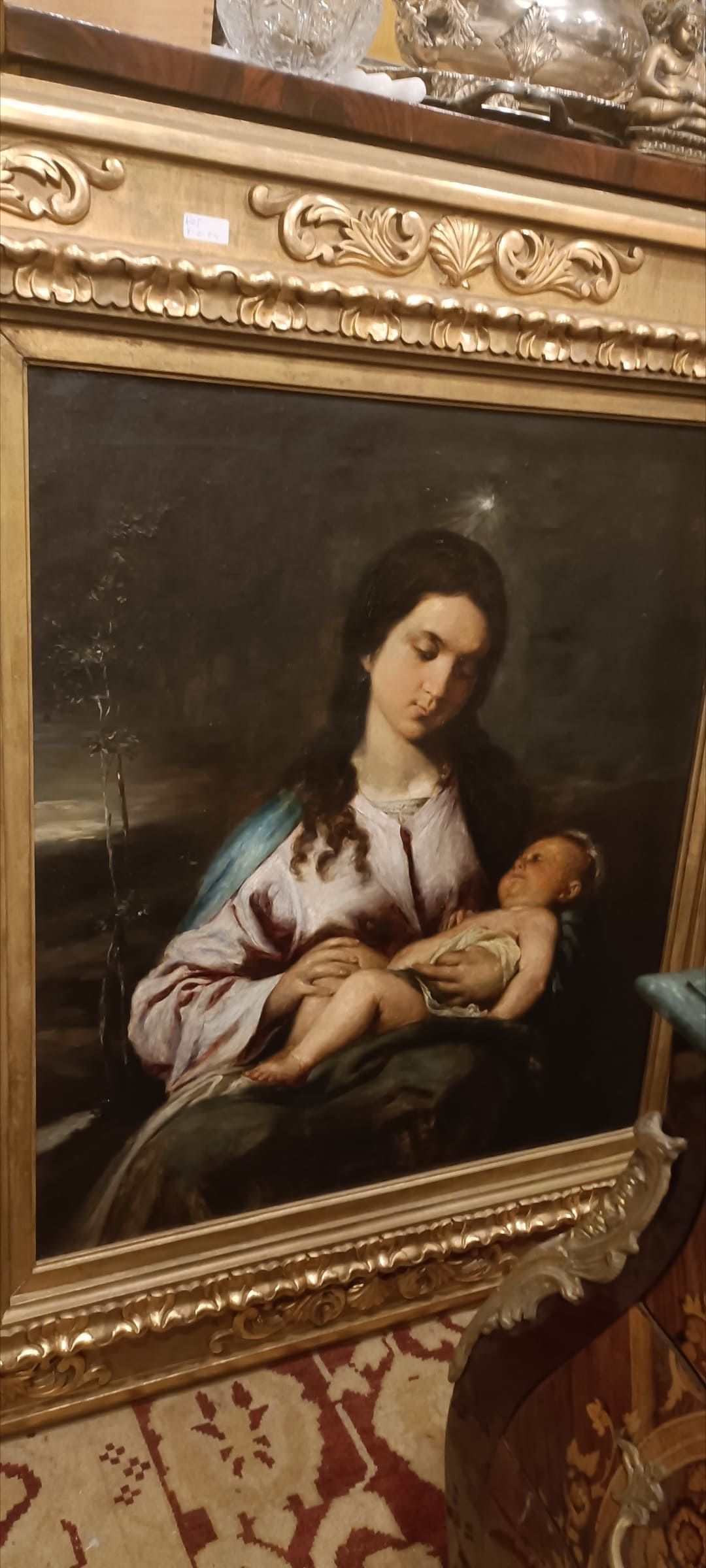 Un cuadro de una mujer sosteniendo un bebé en un marco dorado.