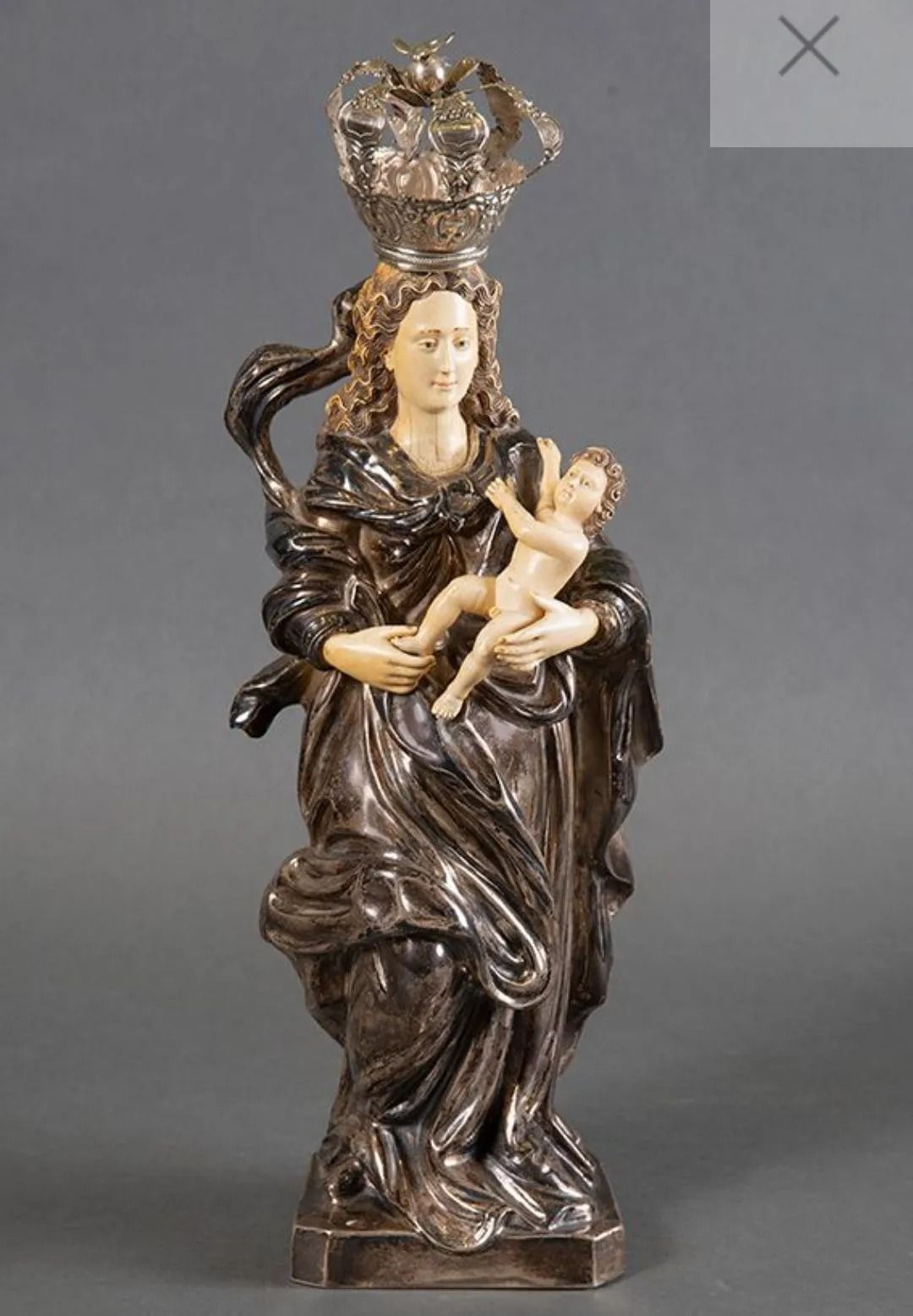 Una estatua de una mujer sosteniendo un bebé con una corona en la cabeza.