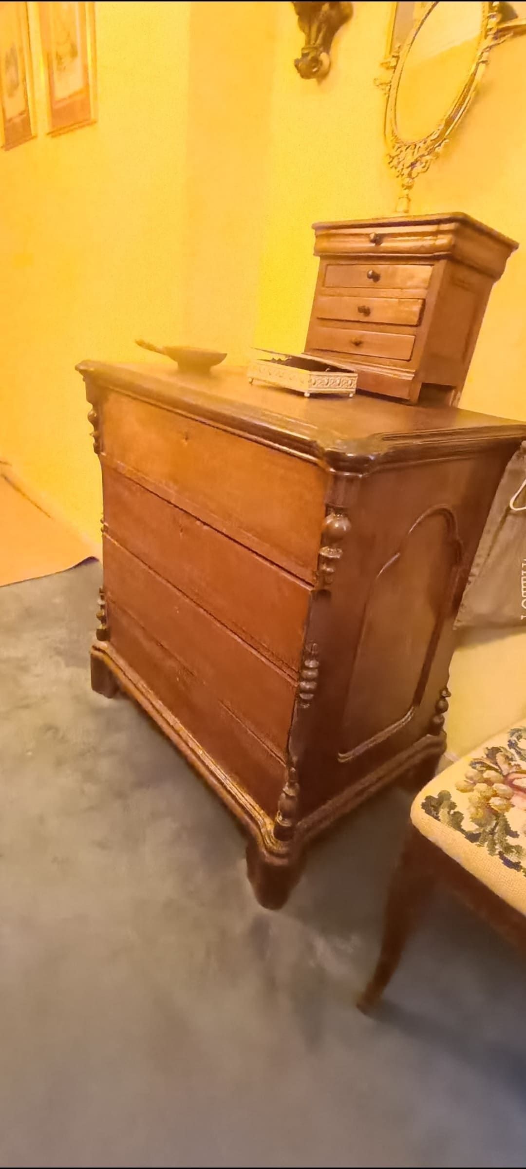 En una habitación hay una cómoda de madera al lado de una silla.