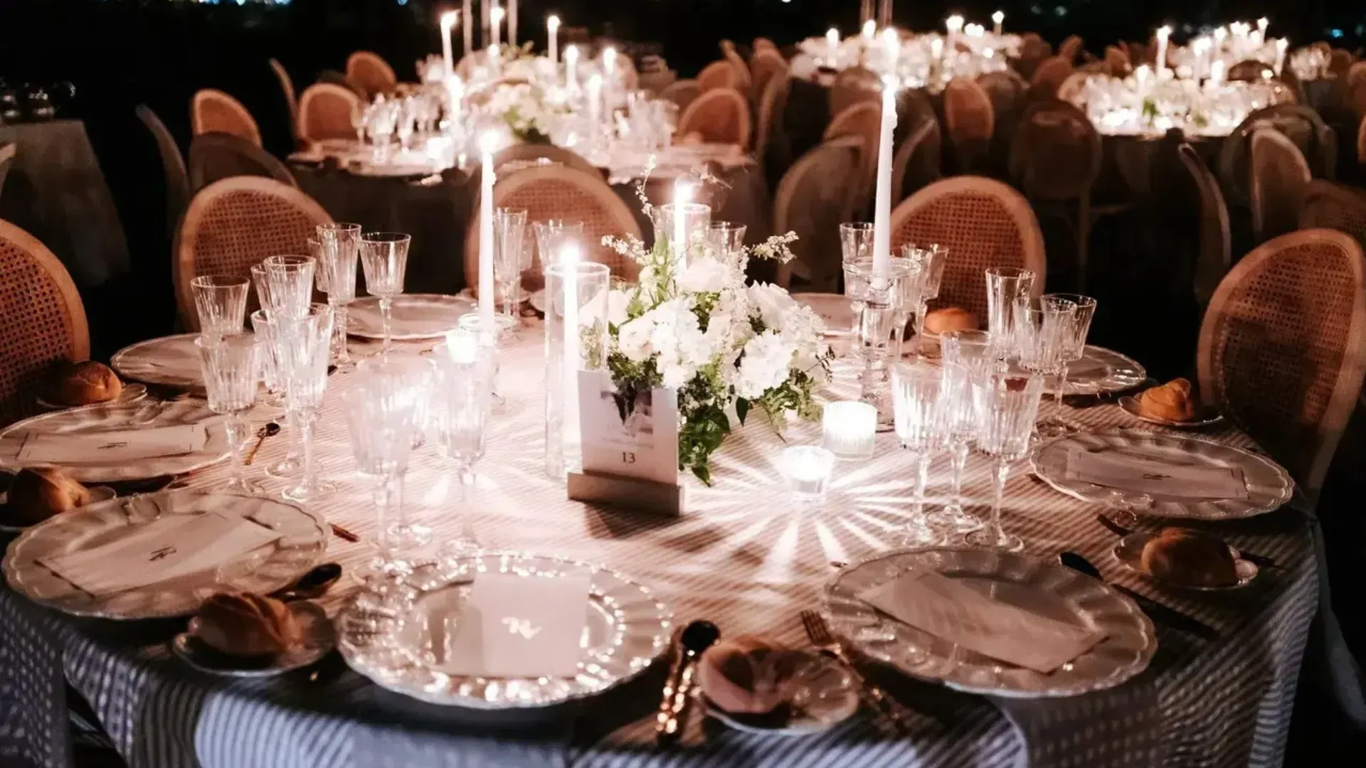 Mesa de comedor formal preparada para un evento especial con velas, flores y elegantes cubiertos.