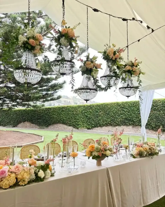 Pareja besándose bajo un velo, sosteniendo un ramo, afuera de un edificio.