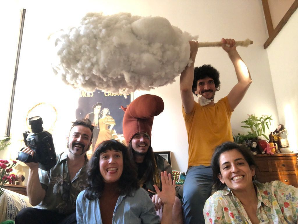 Grupo de cinco personas en un interior, posando con una nube sostenida sobre sus cabezas.