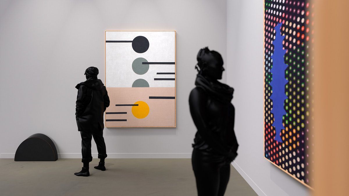 Dos personas mirando pinturas abstractas coloridas en una galería.