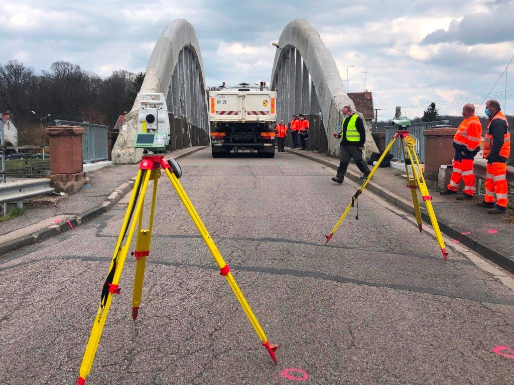 Scanner laser sur trépied surplombant une rue et des bâtiments de la ville au coucher du soleil.