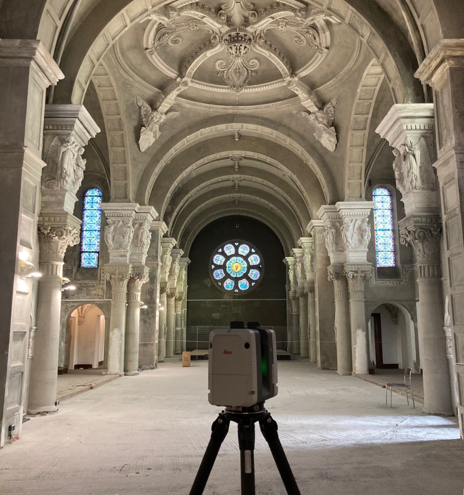Vue intérieure d'une église à l'architecture ornée, avec un scanner laser sur trépied au premier plan.