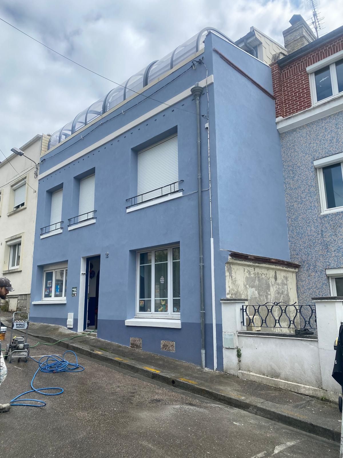 Gros plan sur un façadier qui applique une peinture sur une façade.