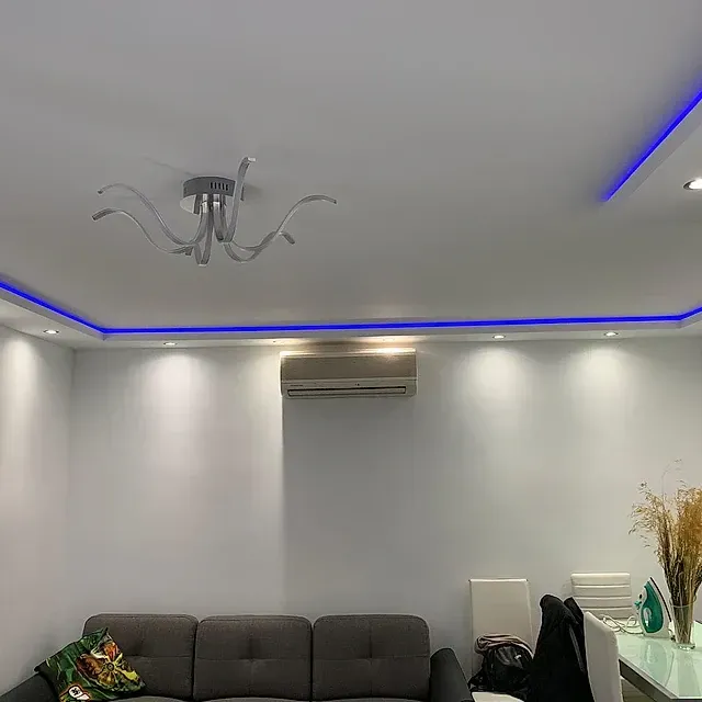 Una sala de estar con un sofá, una mesa, sillas y una lámpara de araña.
