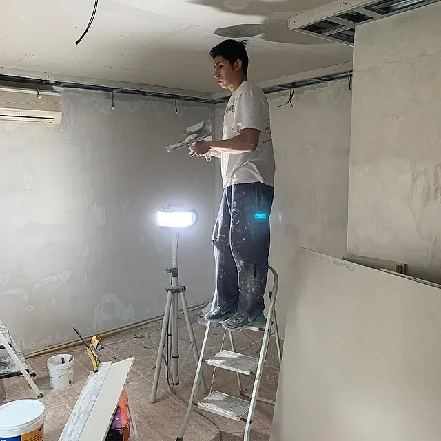 Un hombre está de pie en una escalera en una habitación.