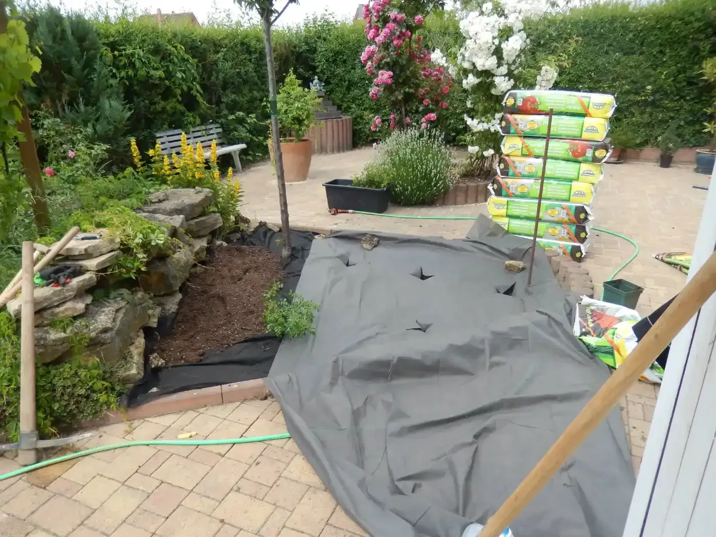 Ein Haufen Säcke mit Erde sind in einem Garten übereinander gestapelt