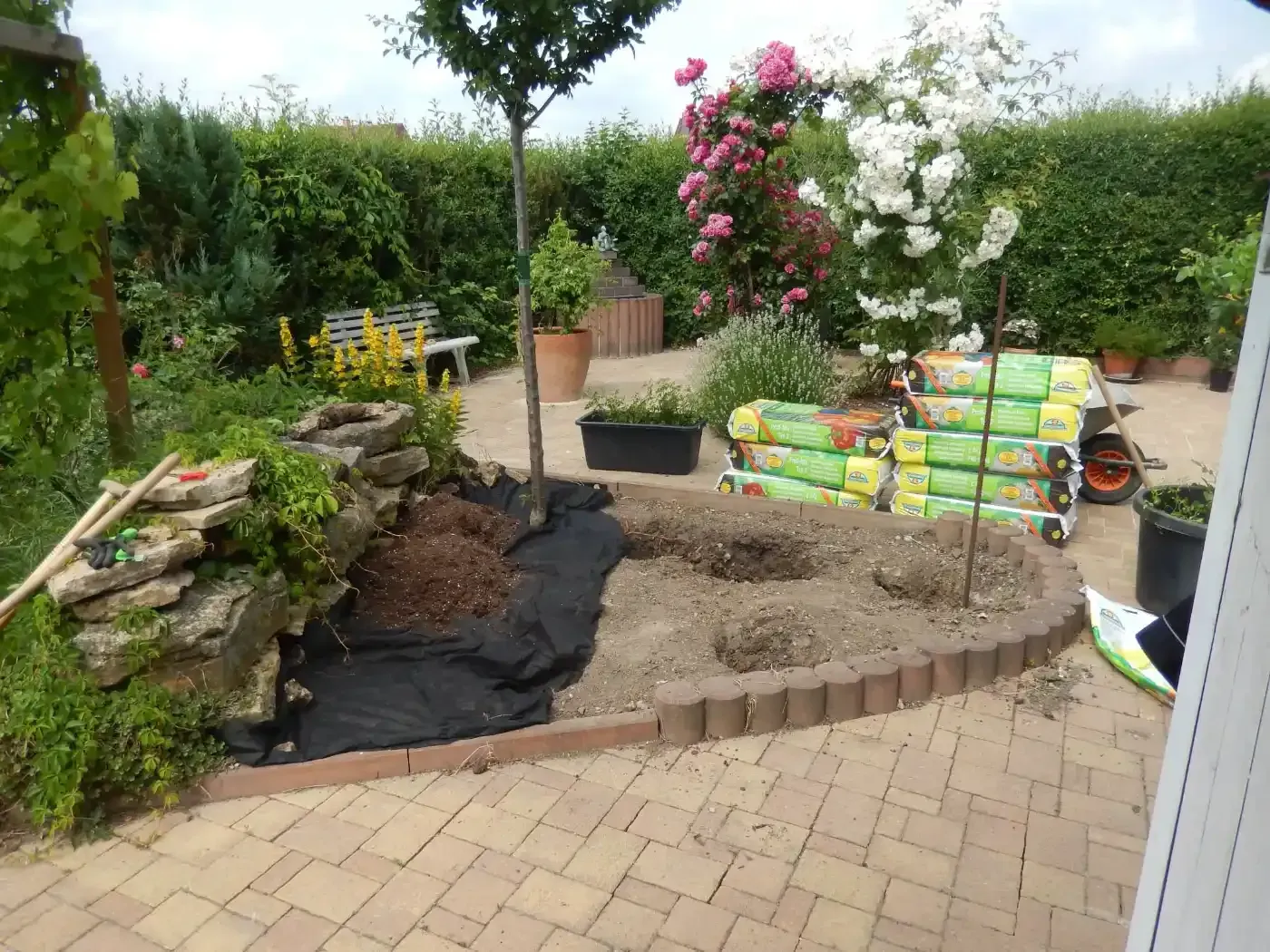 Ein Garten mit vielen Säcken Erde und Pflanzen