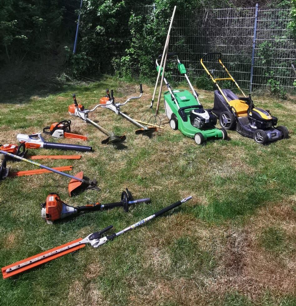 Eine Gruppe von Rasenmähern und Trimmern steht auf einem üppigen grünen Rasen.