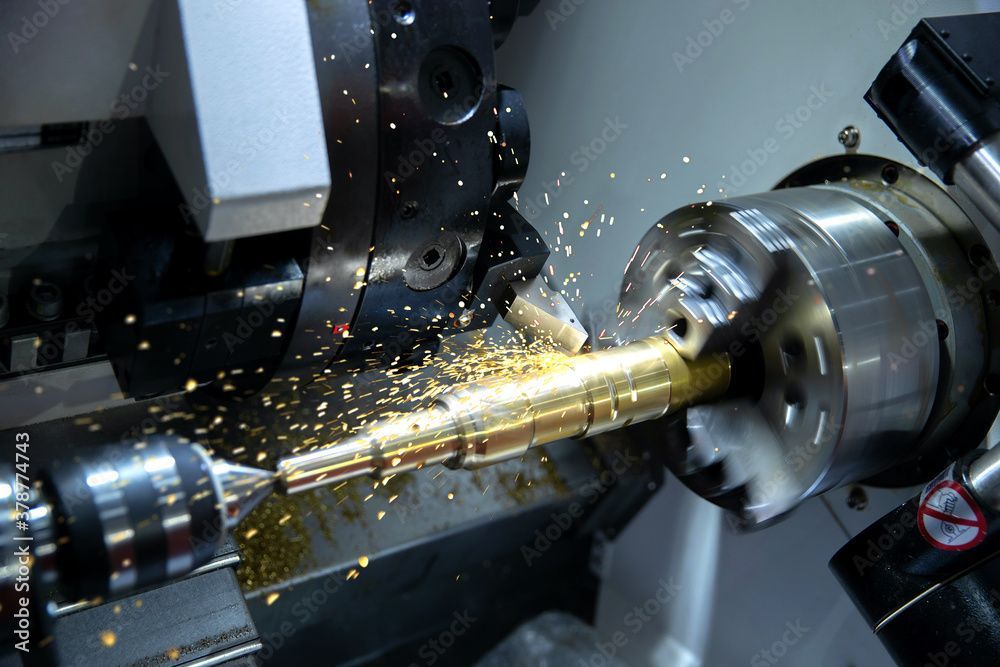 Metalldrehmaschine bearbeitet eine Messingstange, Funken sprühen in einer Industriewerkstatt.
