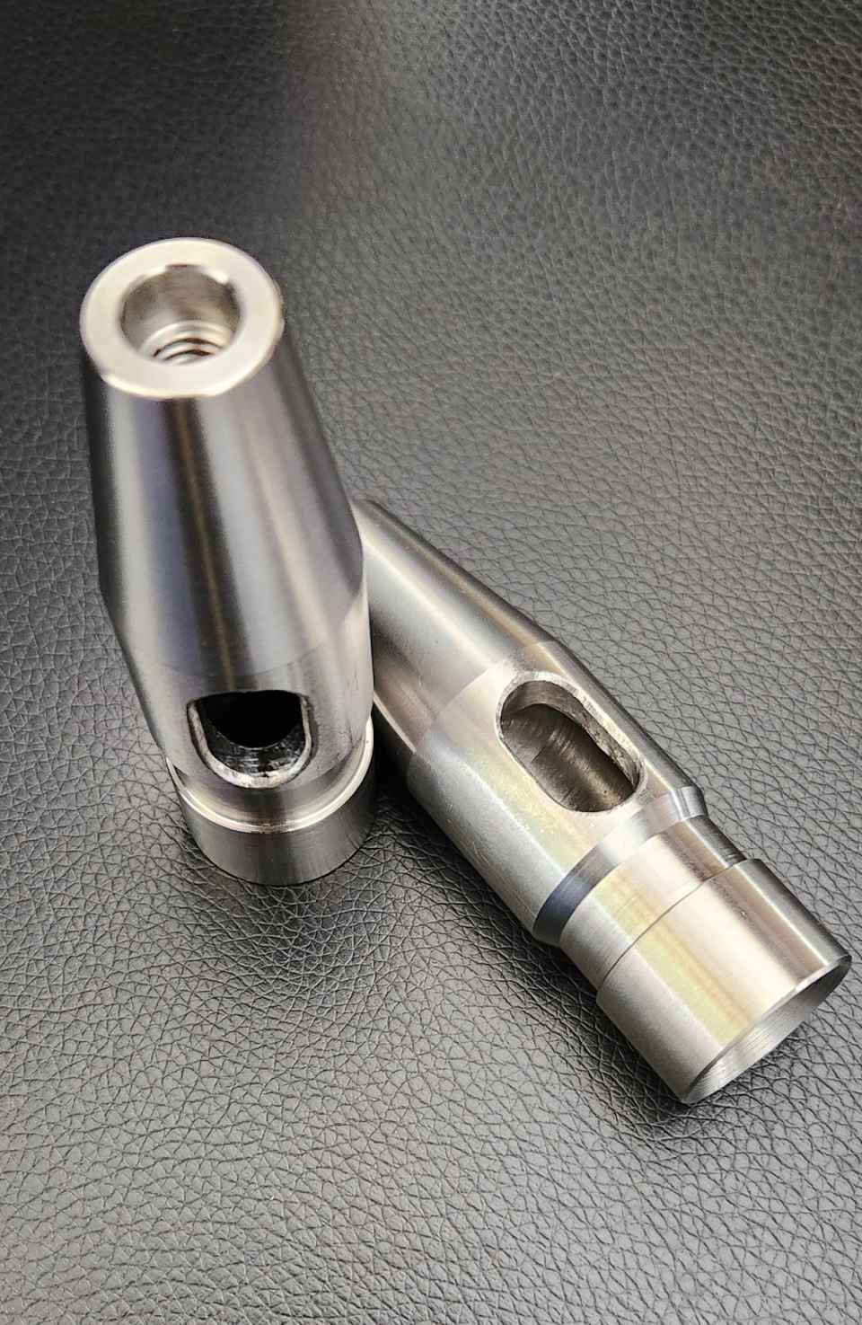 Zwei silberne Metallwerkzeugbits auf einer schwarzen, strukturierten Oberfläche, eines aufrecht und eines liegend.