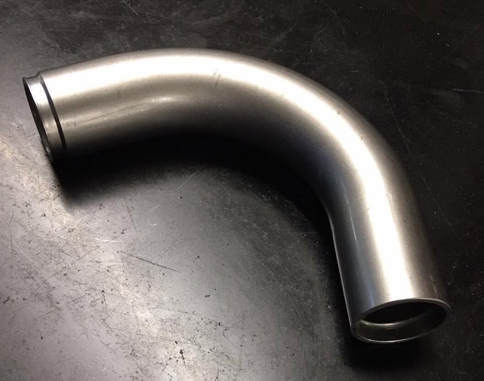 Gebogener weisser Metallhaken mit Löchern und einem kleinen Hakenende auf schwarzem Hintergrund