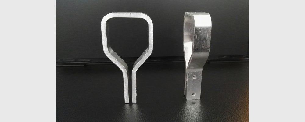 Drei silberne, gebogene Metallrohre mit Messingbeschlägen auf dunklem Untergrund.
