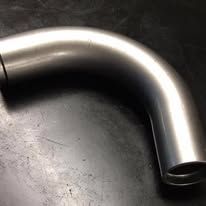 Gebogener weisser Metallhaken mit Löchern und einem kleinen Hakenende auf schwarzem Hintergrund