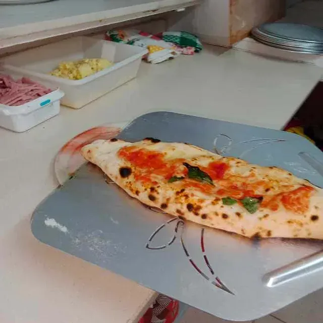Una pizza está colocada encima de una bandeja de metal sobre un mostrador.