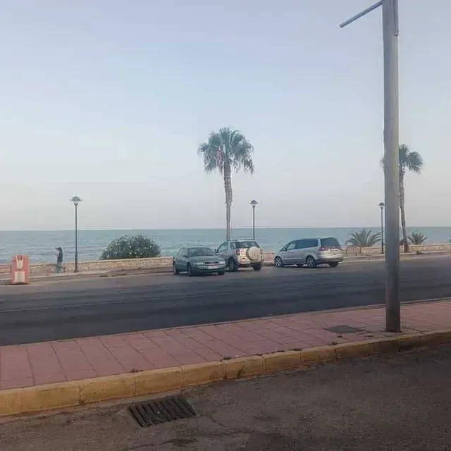 Los coches están aparcados al costado de la carretera cerca del océano.