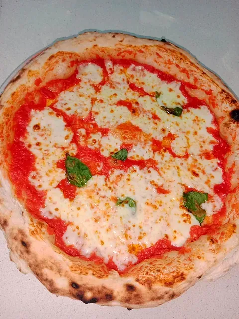 Una pizza con salsa de tomate y queso está sobre una mesa.