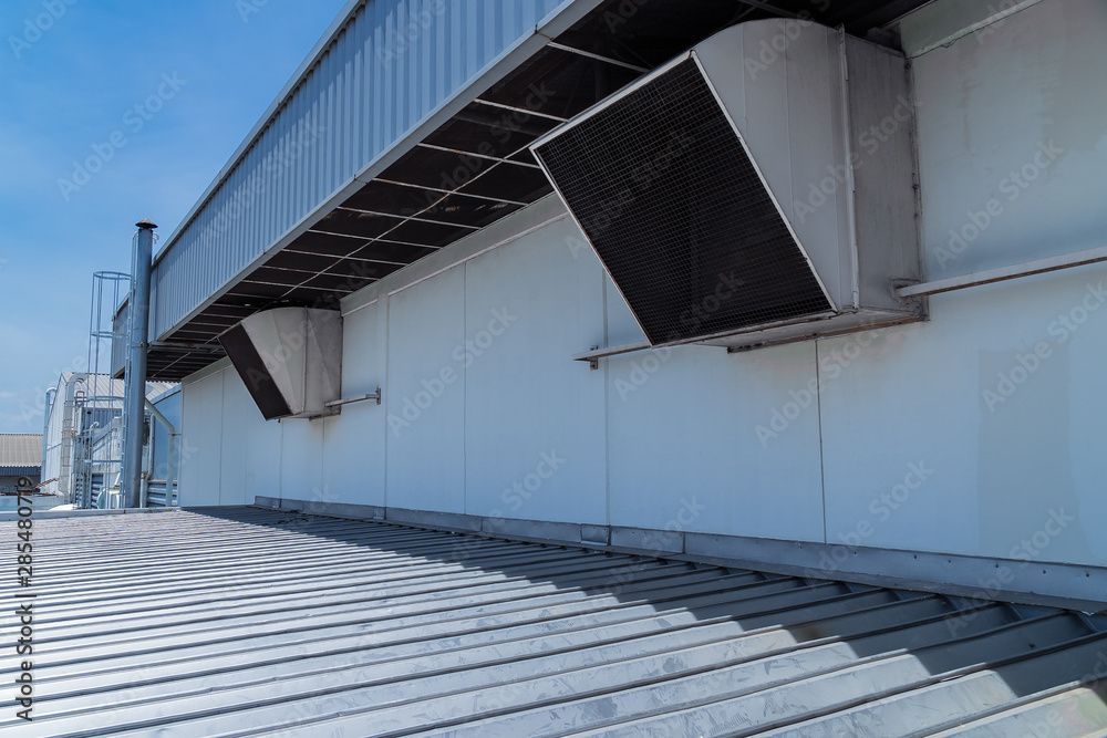 Industriedach mit grossen Lüftungsanlagen und Wellblechdach unter blauem Himmel