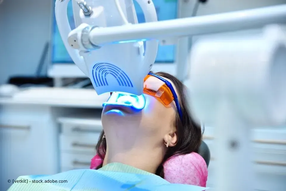 Patient mit Schutzbrille erhält blaues Licht zur zahnärztlichen Behandlung im Behandlungsstuhl