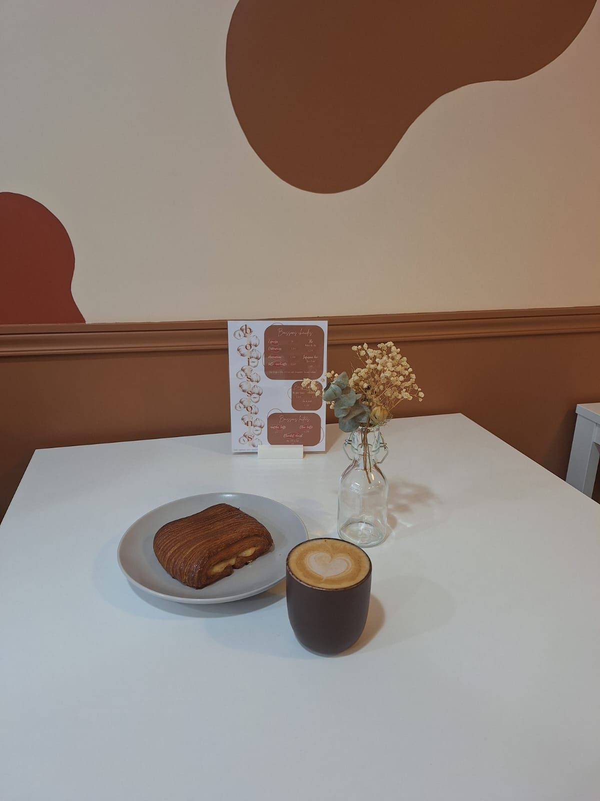 Viennoiserie et café posés sur une table blanche.