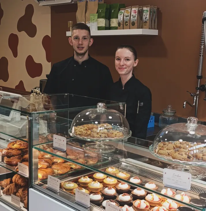Comptoir de boutique avec pâtisseries et les deux gérants derrière le comptoir.