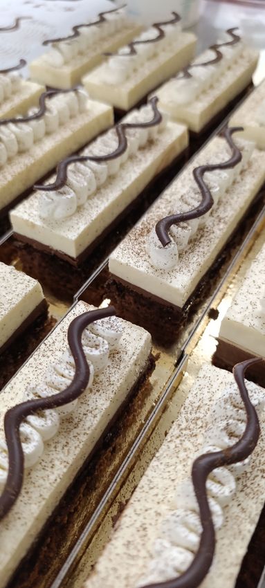 Des rangées de pâtisseries individuelles rectangulaires nappées de chocolat disposées sur un plateau.