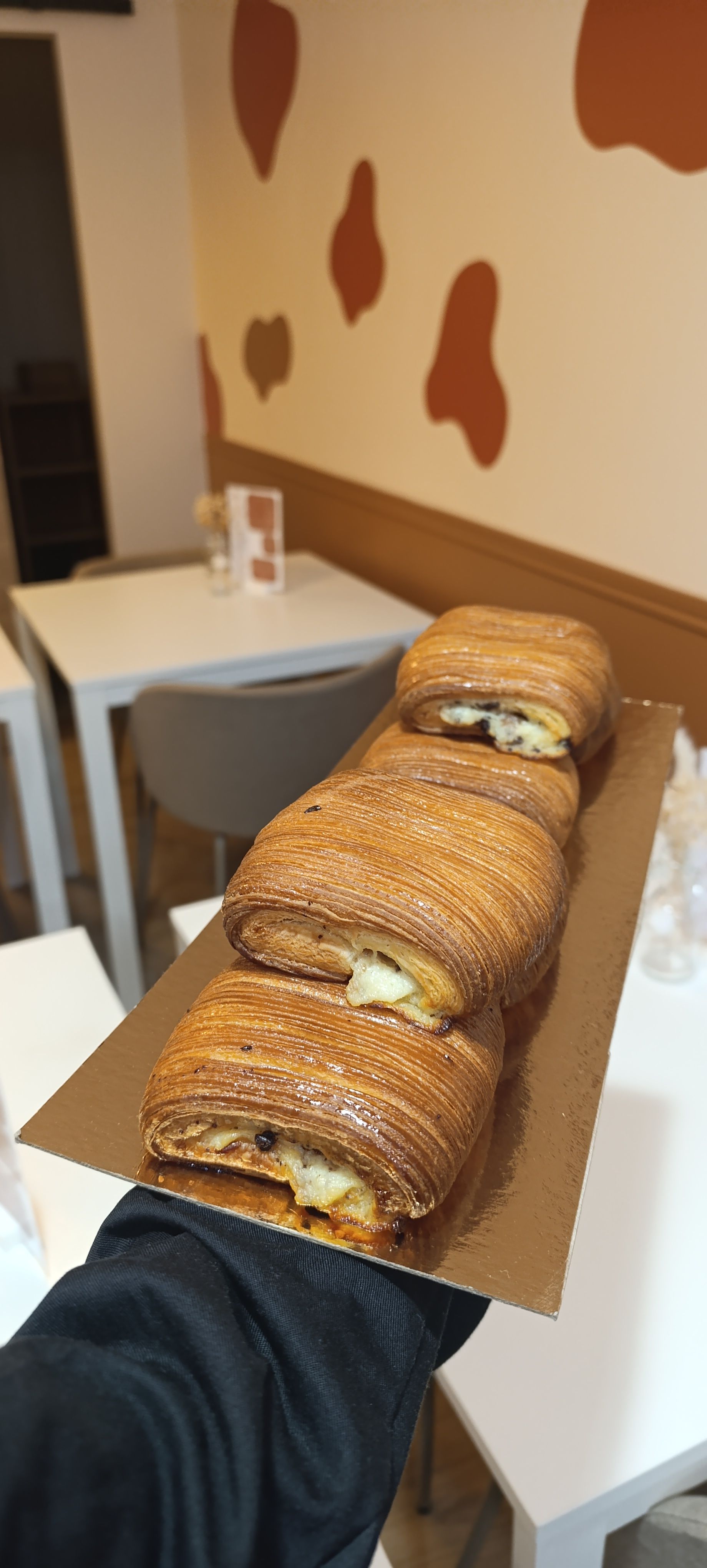 Mains tenant un plateau avec plusieurs viennoiseries.