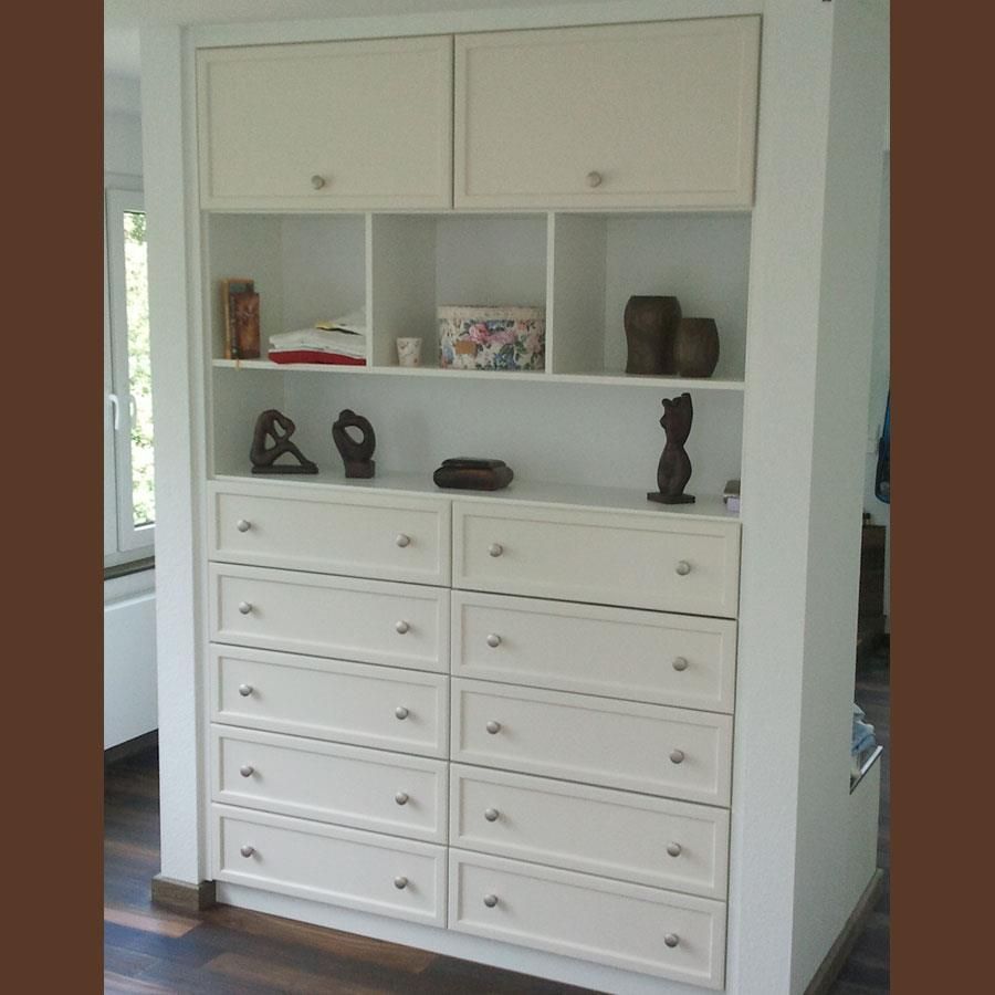Eine weiße Kommode mit vielen Schubladen und Regalen