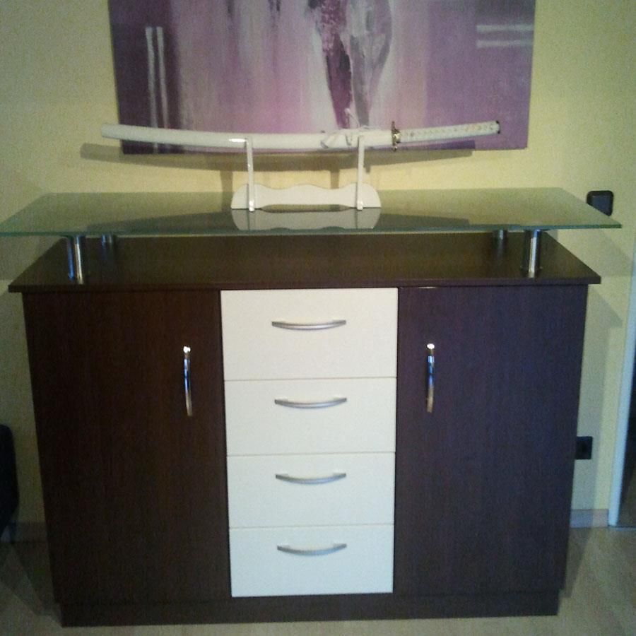 Ein braun-weißer Schrank mit Schubladen und einer Glasplatte, in dem ein Katana liegt.