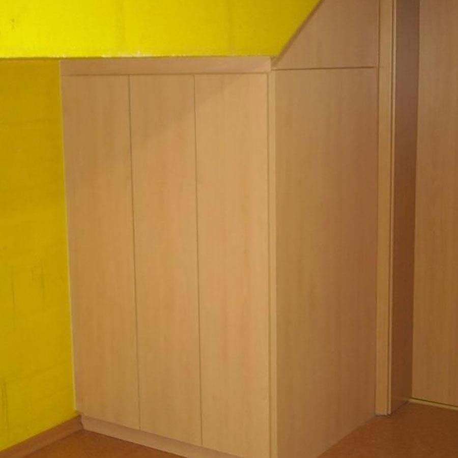 Ein Holzschrank in einem Raum mit gelben Wänden und einer Tür.