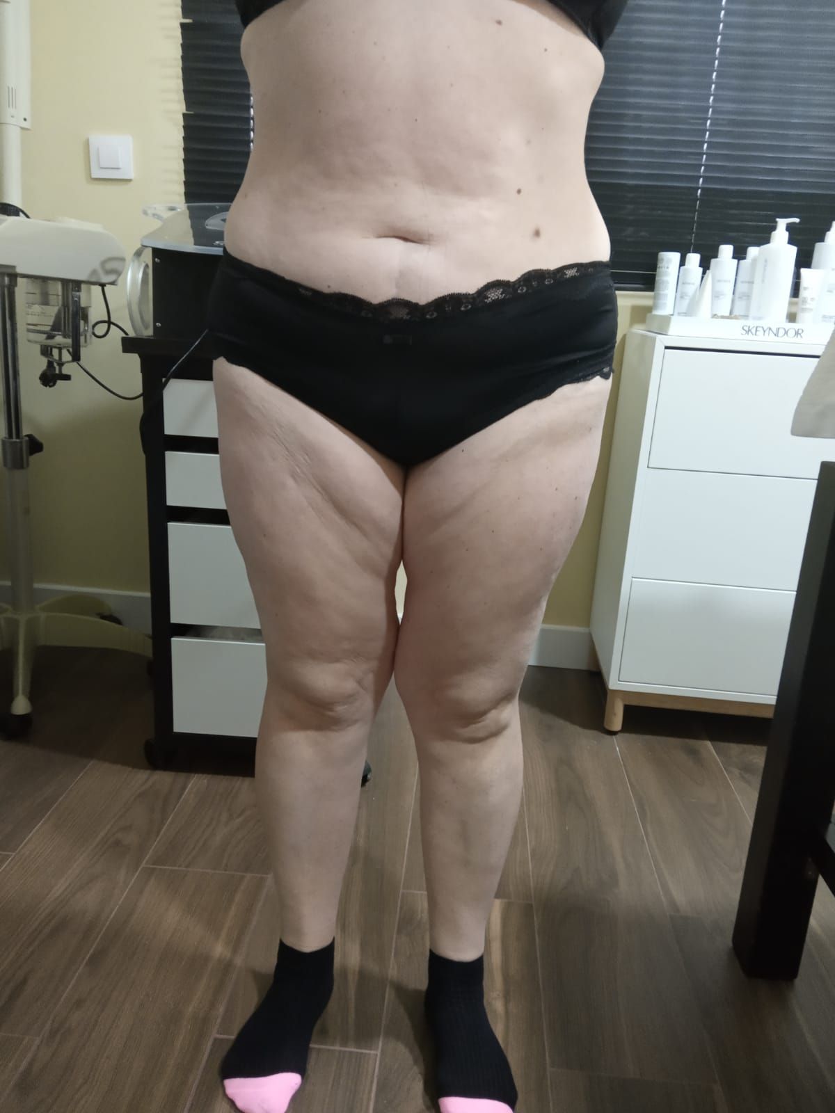 Una mujer en ropa interior negra y calcetines rosas está de pie en una habitación.