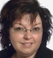 Porträt einer lächelnden Person mit kurzen dunklen Haaren und Brille vor weißem Hintergrund