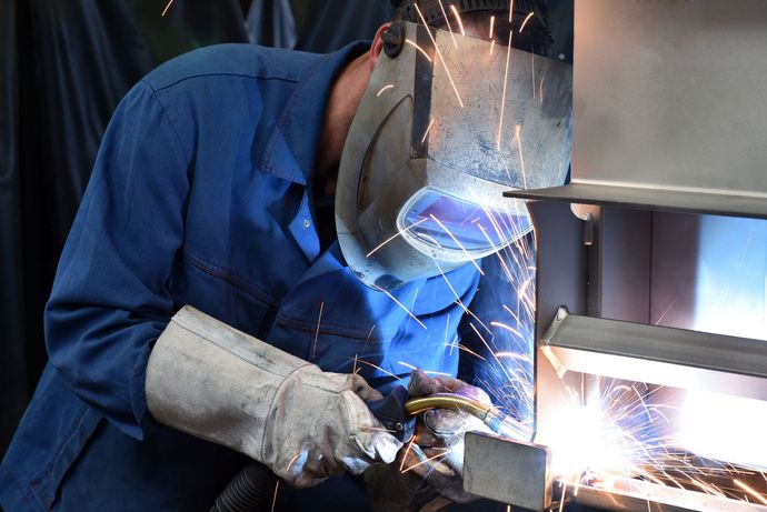 Ein Mann mit einer Schweißmaske schweißt ein Stück Metall.