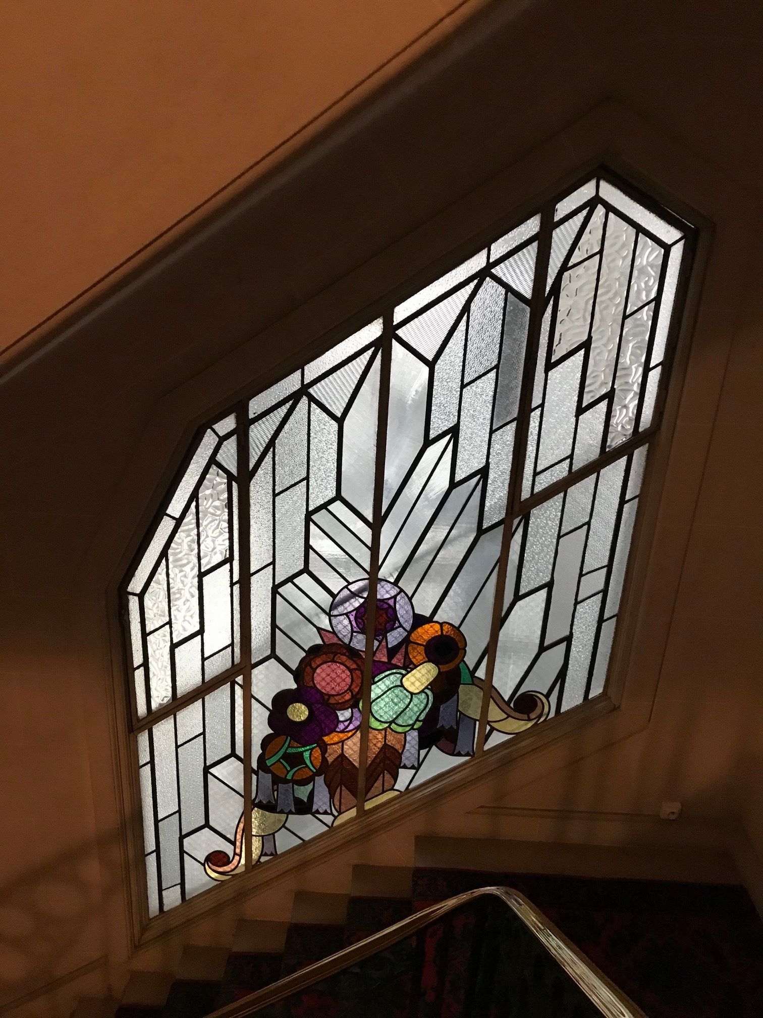 Vitrail à motifs géométriques et floraux, situé au-dessus de l'escalier.