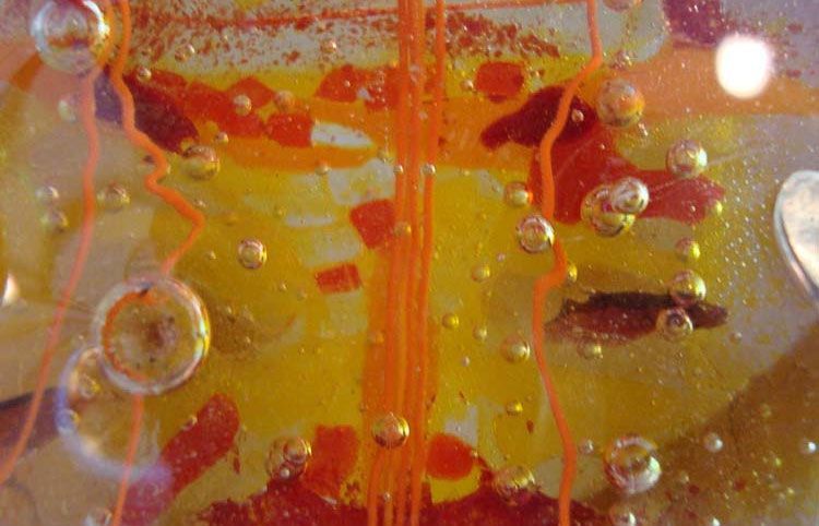 Gros plan sur un Vitrail d'art abstrait coloré, principalement orange, jaune et rouge, avec des bulles et des lignes.